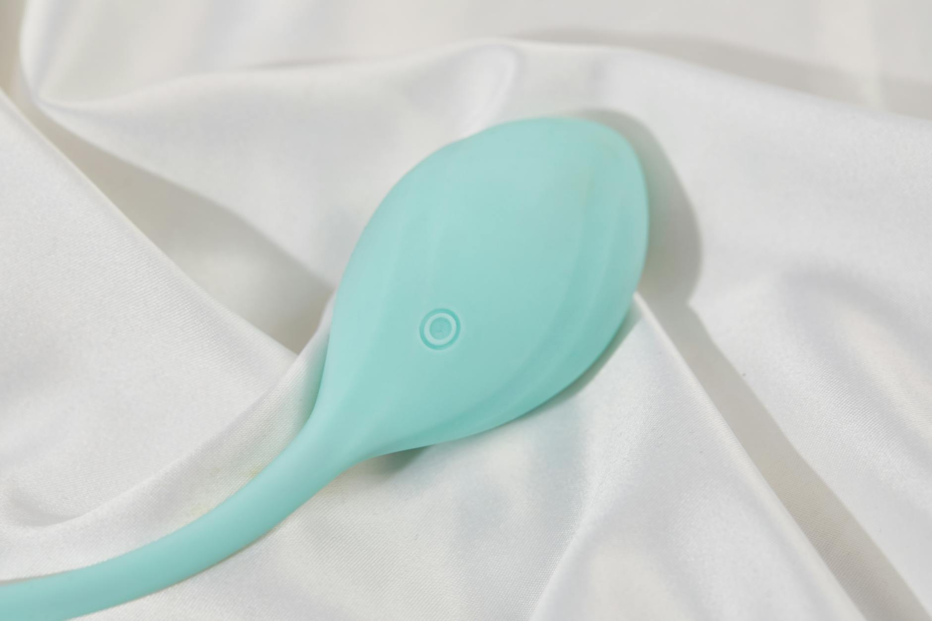 Elegant teal silicone vibrator on soft white silk