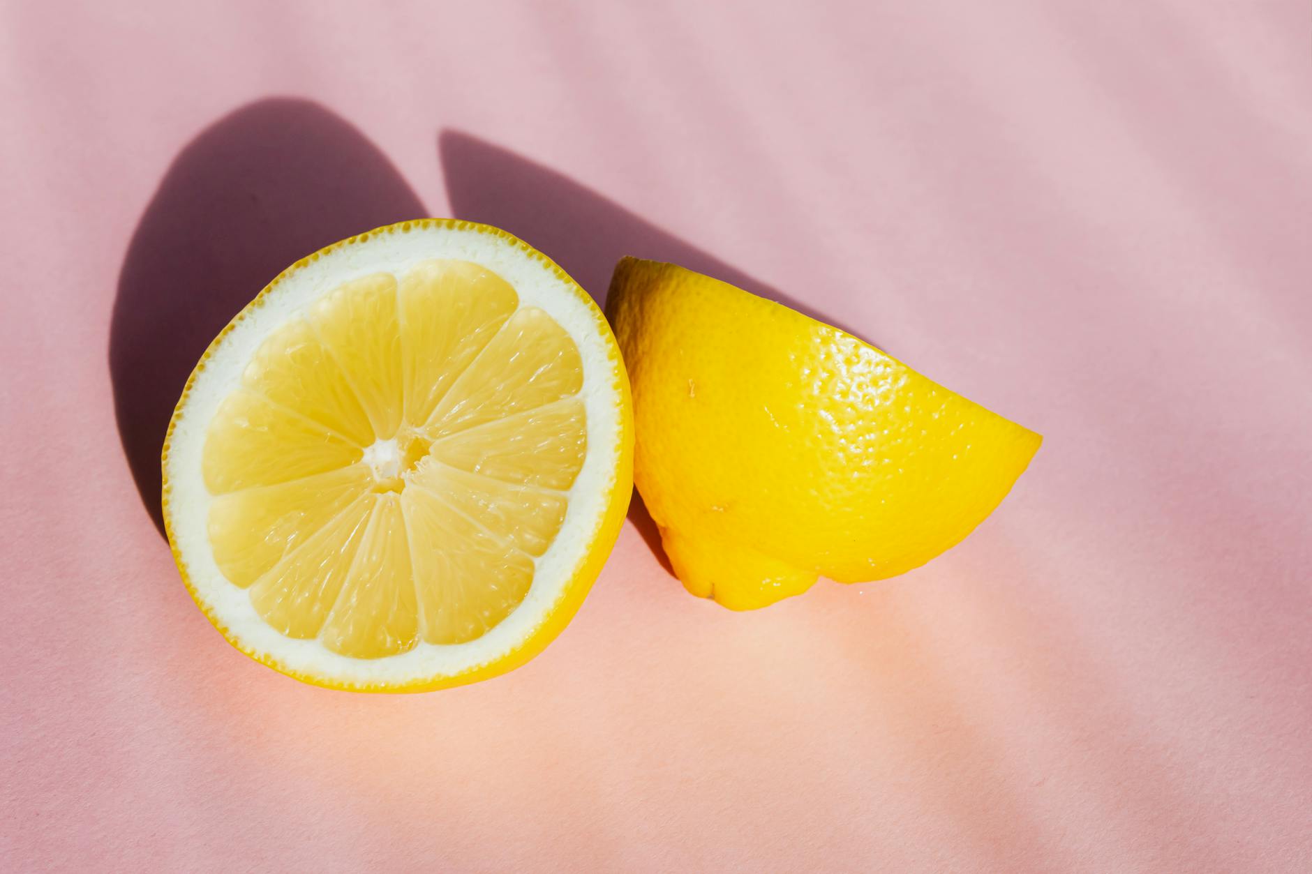 A hand holding a yellow silicone vibrator against a soft pink background