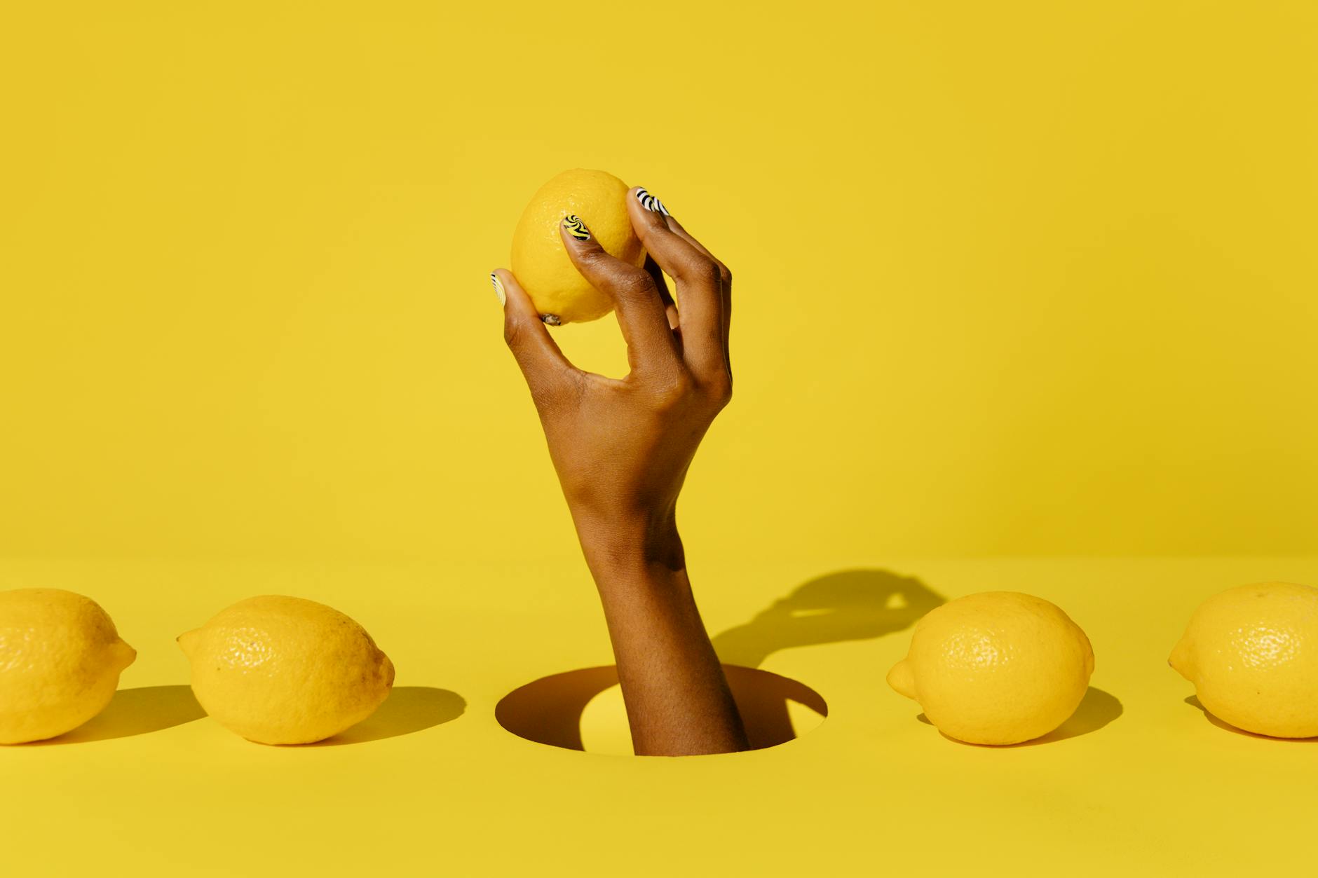 A close-up of a hand holding an orange vibrator against a minimalistic purple backdrop, showcasing modern sensuality.