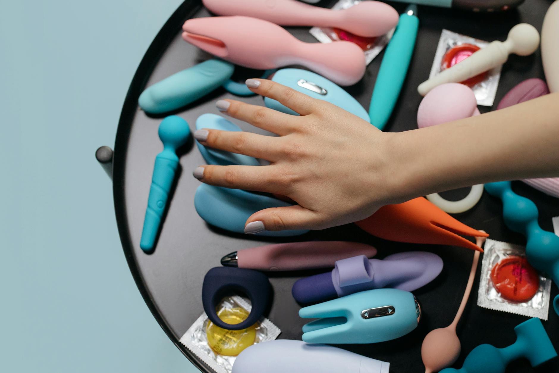 Close-up of a hand holding an orange vibrator against a minimalistic purple backdrop