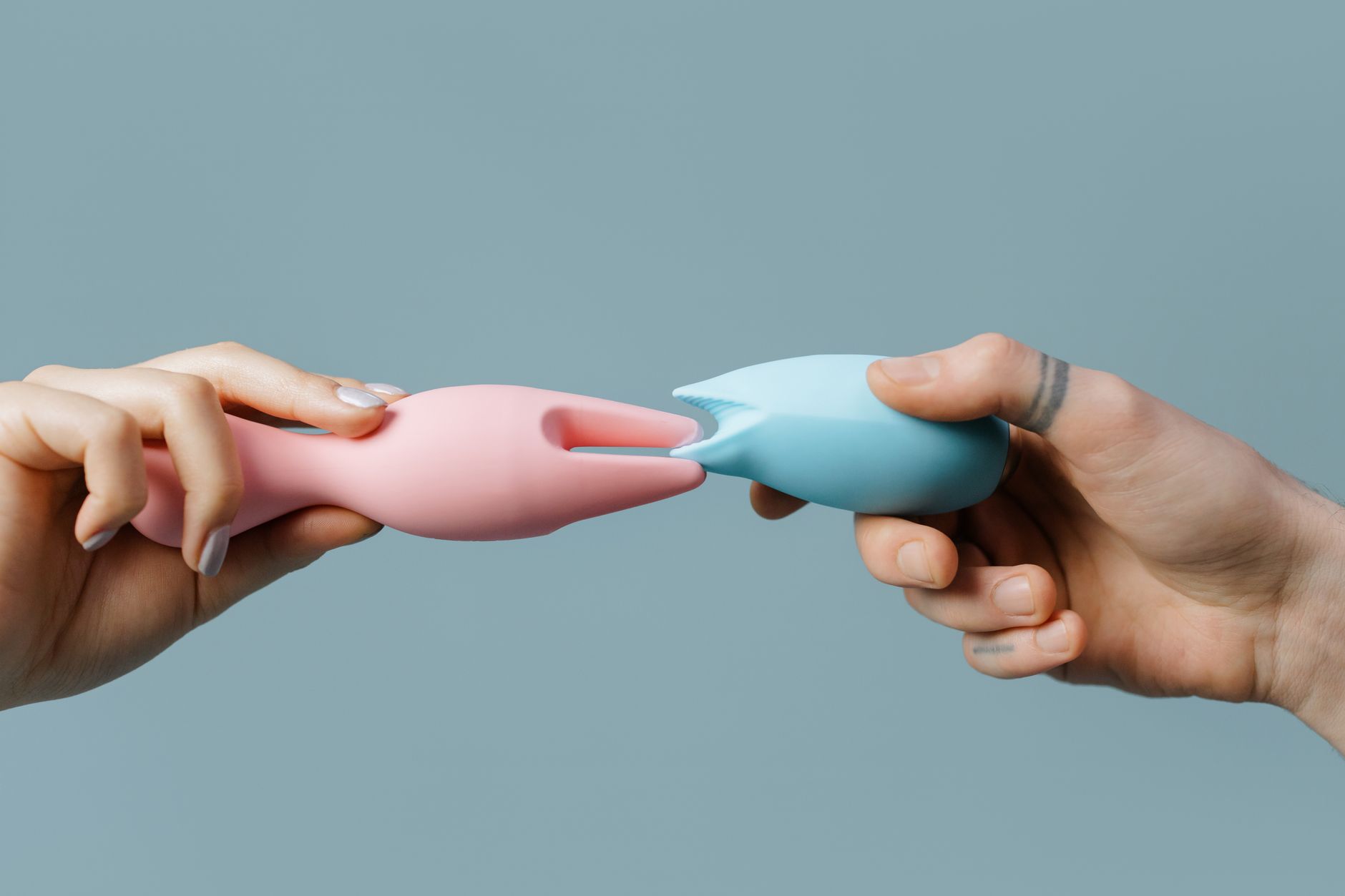Hands holding silicone sex toys in various colors, representing self-care and solo pleasure.