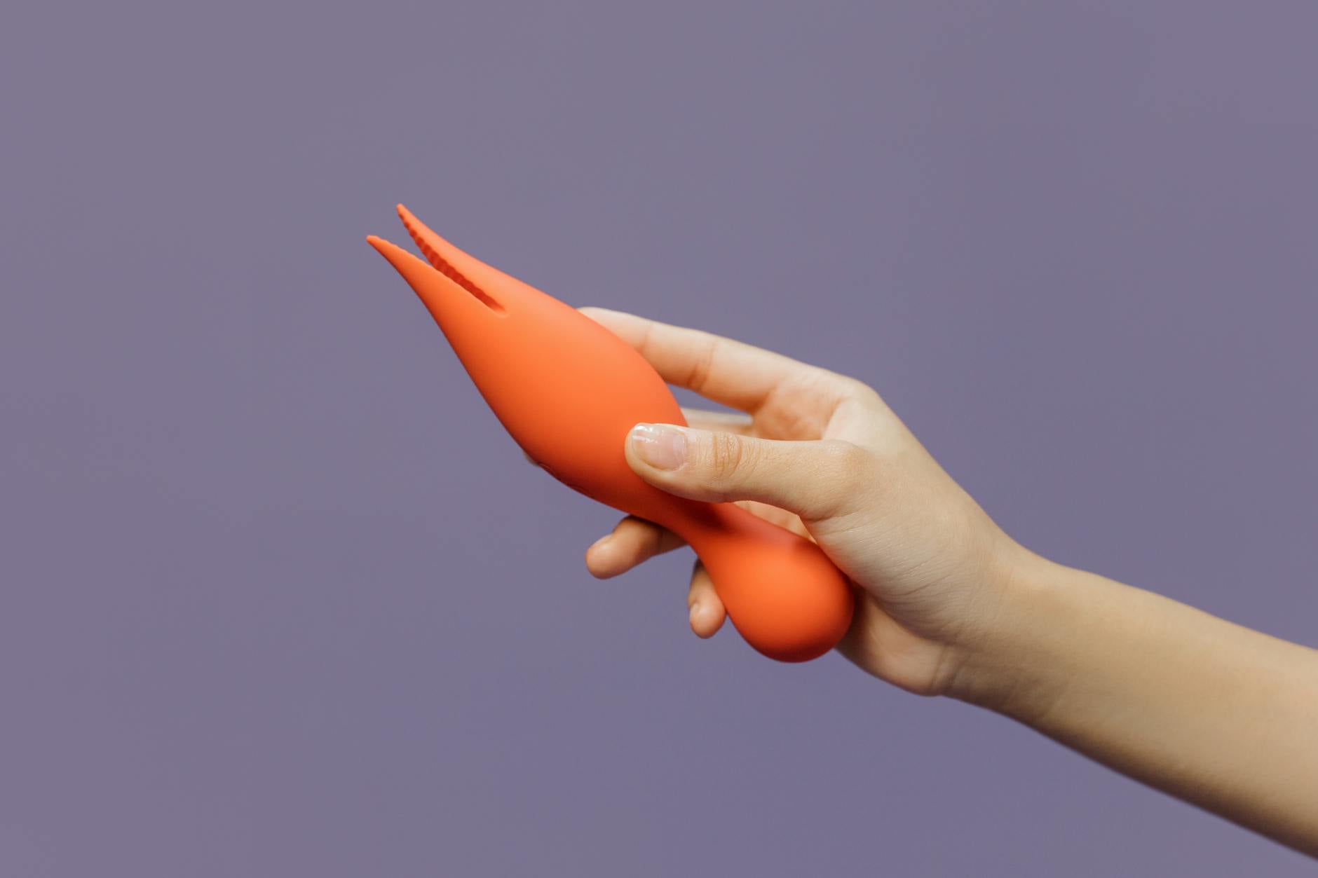 Close-up of hands exploring sensation with a modern lemon vibrator against a minimalist backdrop