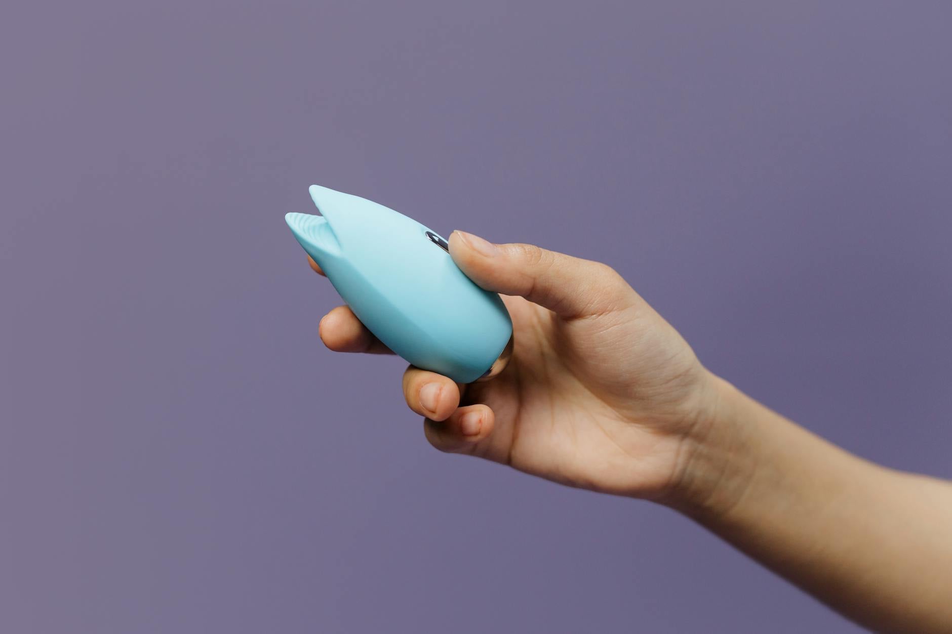 A young couple standing together indoors, holding a vibrator, symbolizing modern intimacy and shared pleasure.