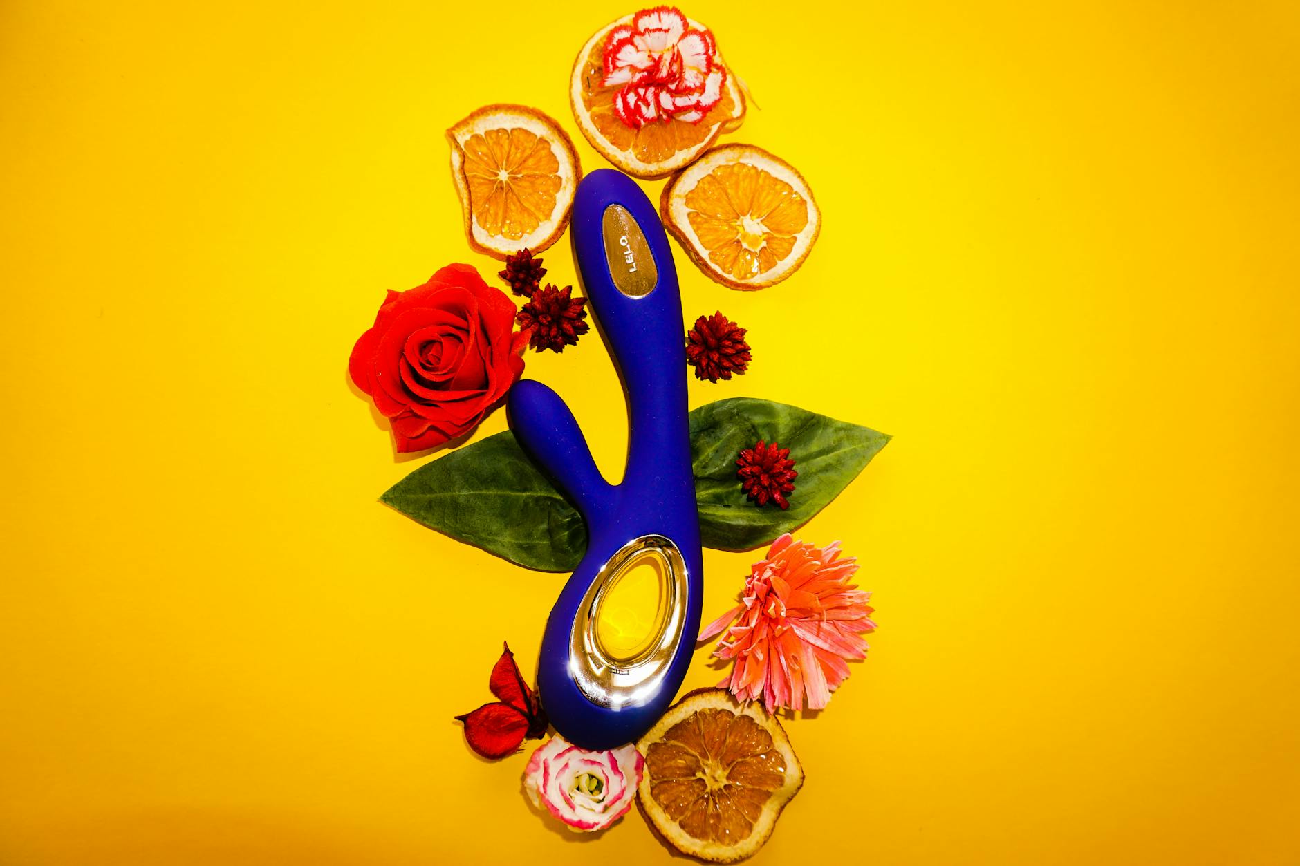 A lemon clitoral vibrator surrounded by fresh lemons and flowers on a bright background, symbolizing renewal and pleasure restoration.
